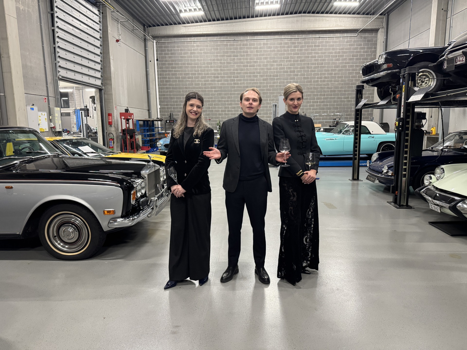 Three guests photographed together among the cars