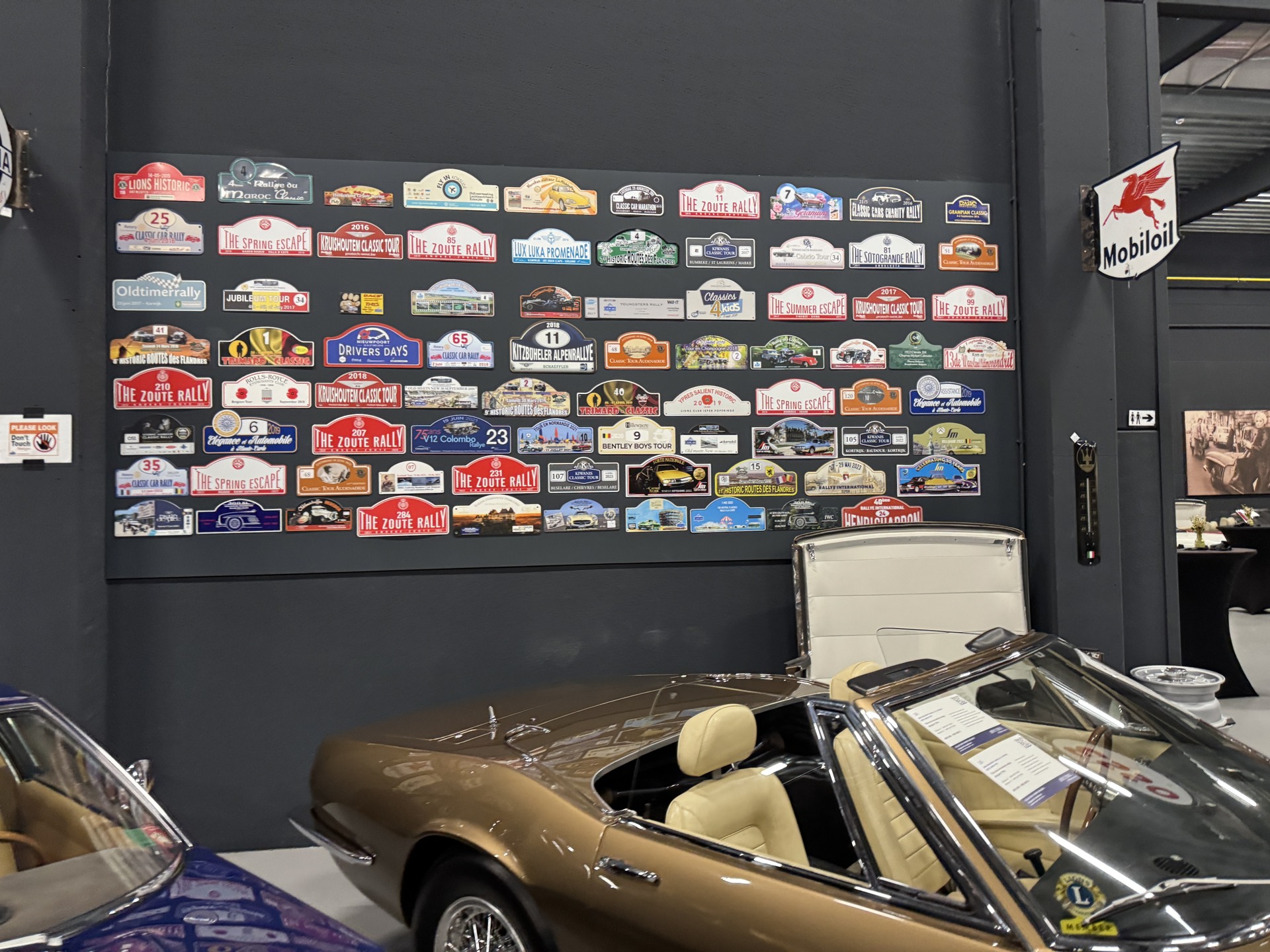 Rally plaques displayed above an open classic car