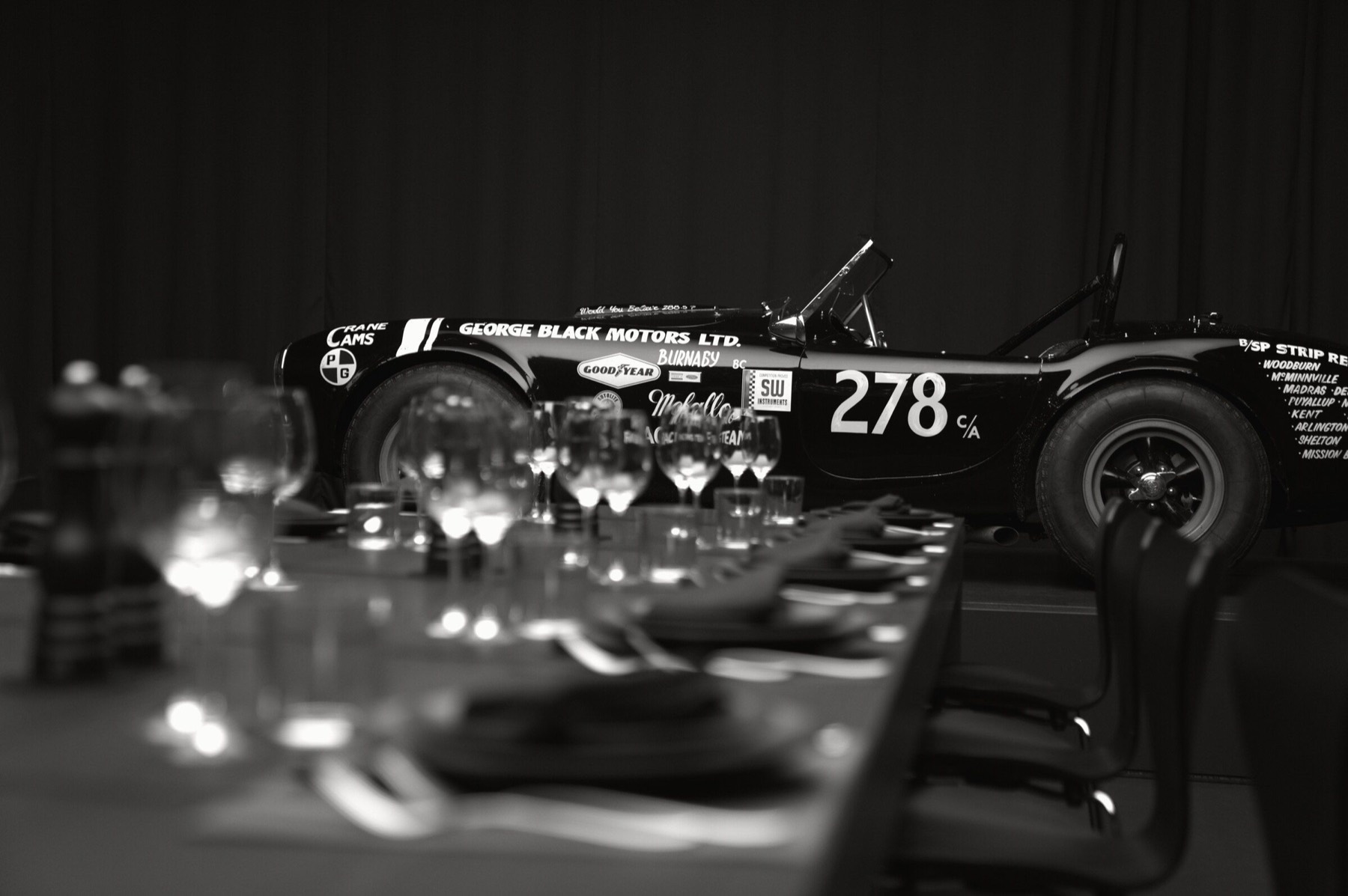 Historic race car beyond the set dinner table.