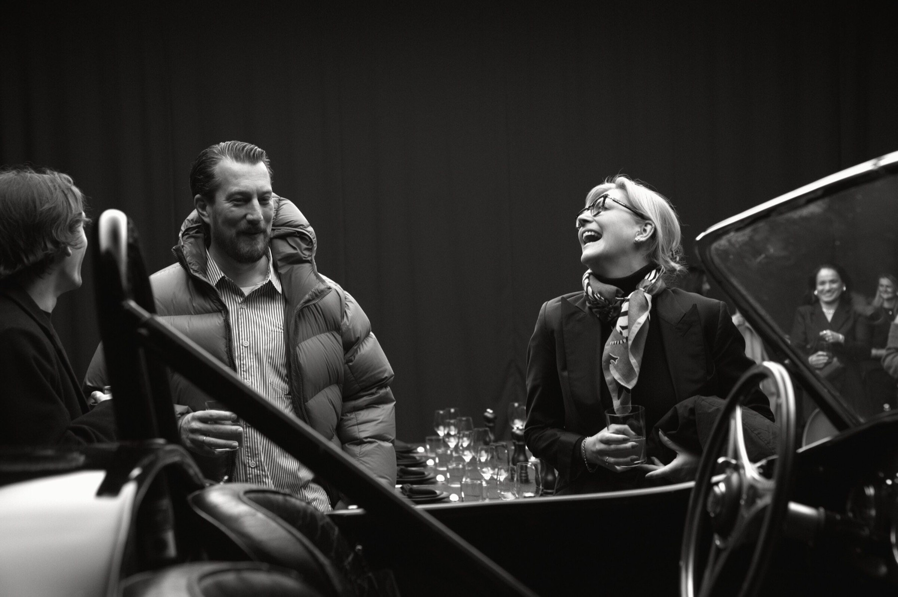 Laura Kukuk von Glahn laughing with guests beside a collector car.