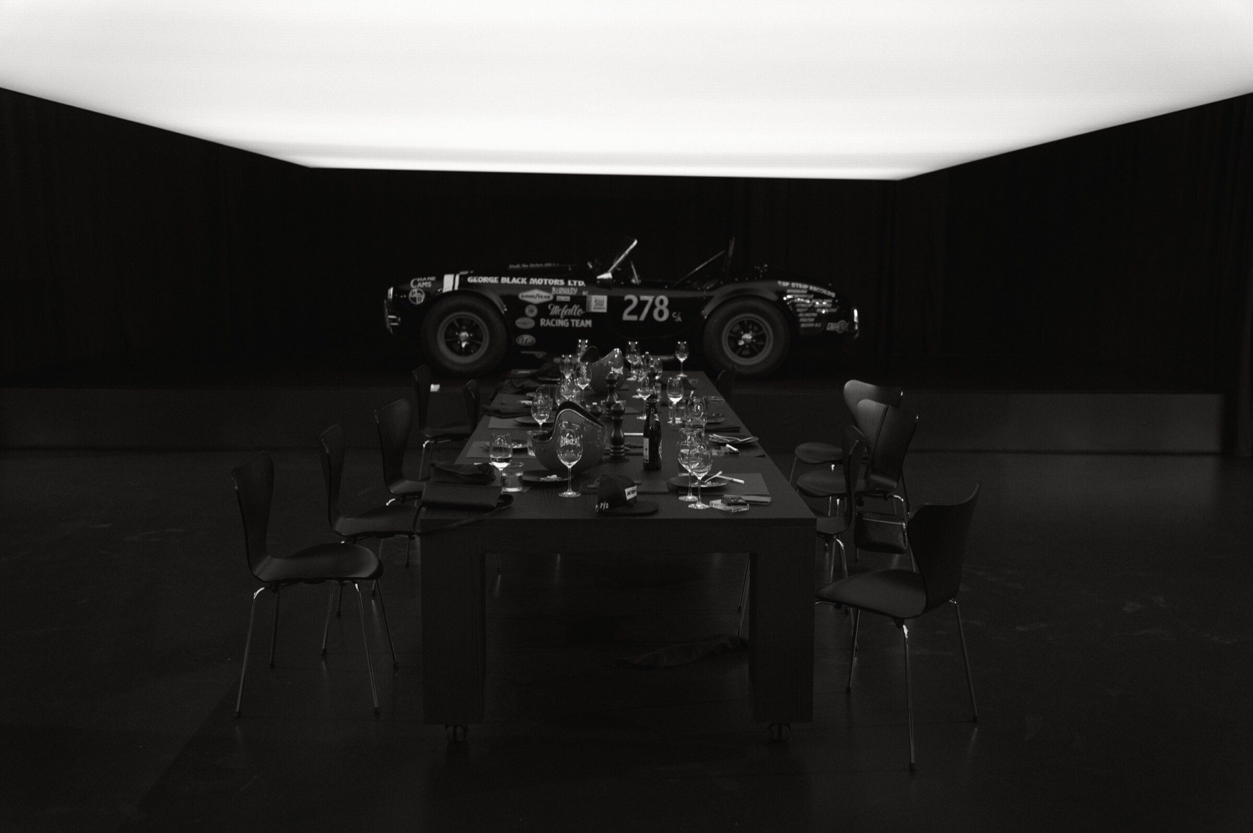 Empty dinner table prepared beneath a luminous ceiling.