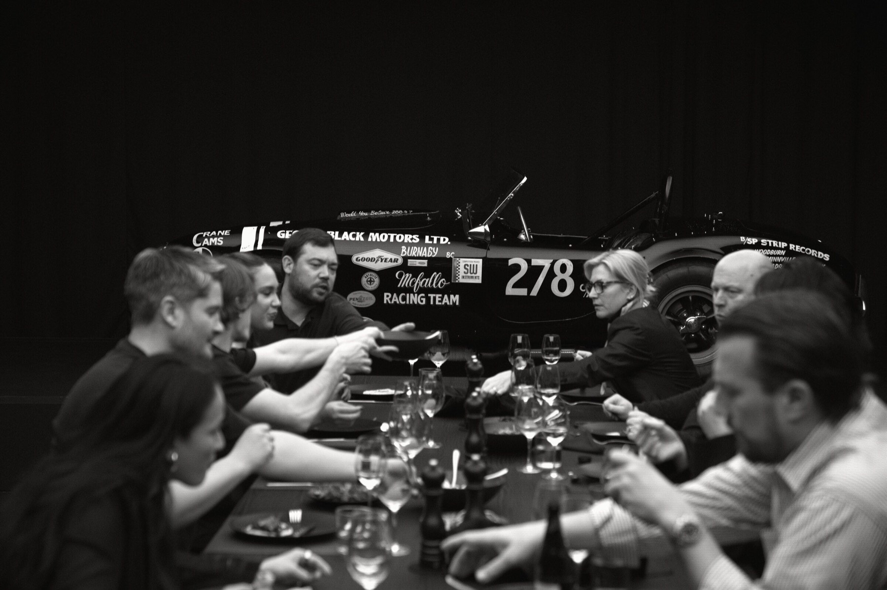 Dinner in progress with a historic race car behind the guests.